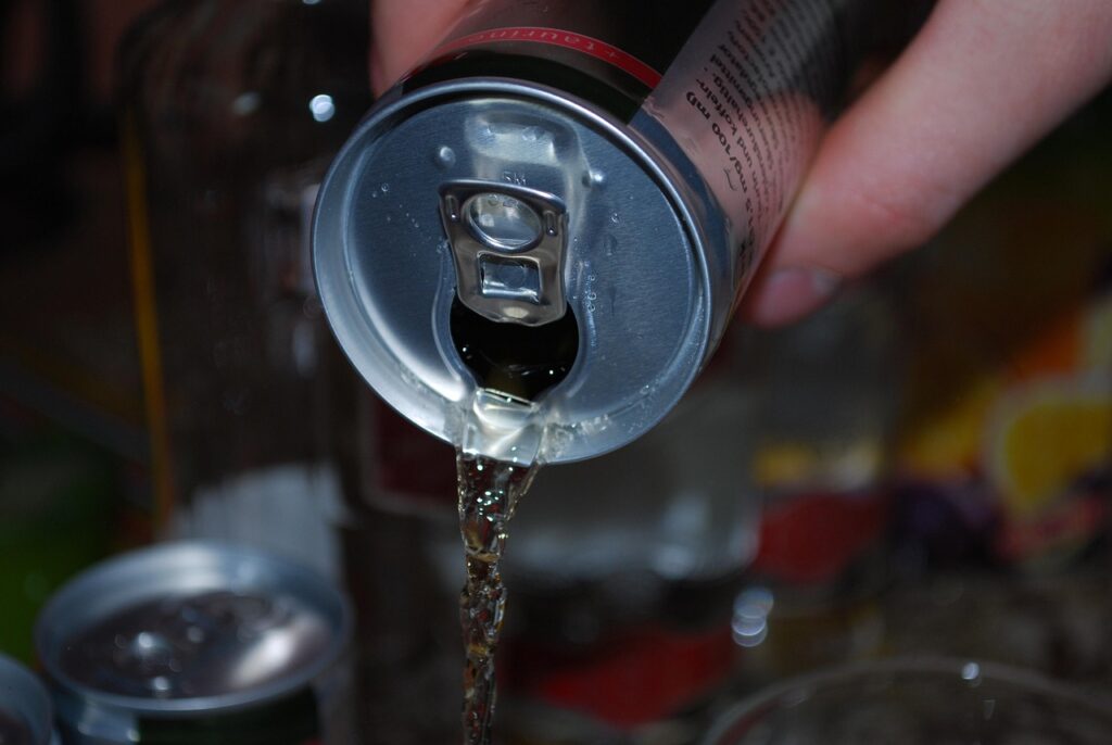 Una mano che versa un energy drink in un bicchiere