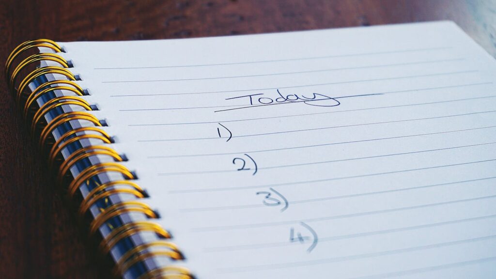 4 Tecniche per adattare il calendario agli imprevisti senza perdere il ritmo nello studio 2 A close-up view of a handwritten to-do list on a spiral notebook with numbers for tasks.