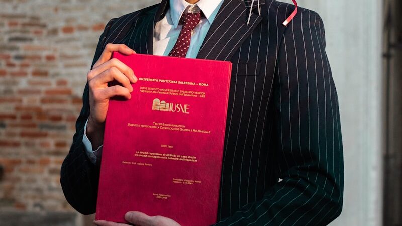 man in black suit holding red book